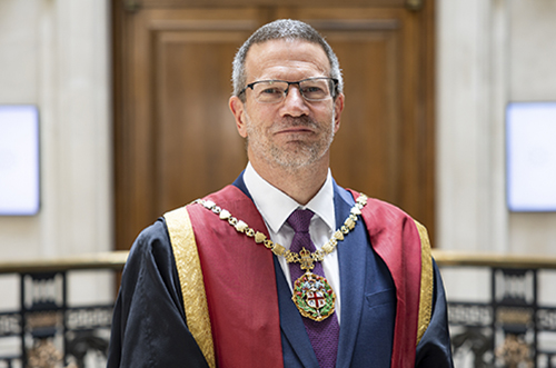 man wearing graduation gown and large chain